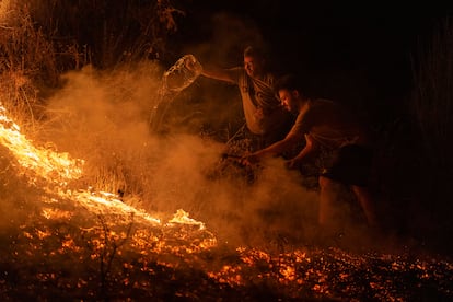 Vecinos de la localidad trabajan la madrugada de este domingo en labores de extinción del incendio forestal de A Rúa (Ourense).