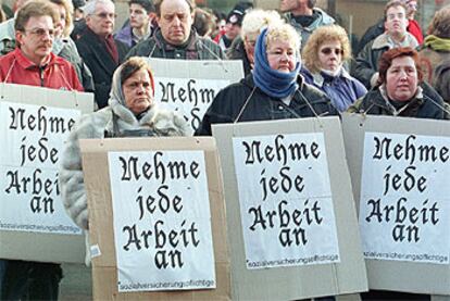 Un grupo de personas en paro solicitan en los carteles: "Me conformo con cualquier oferta de empleo".