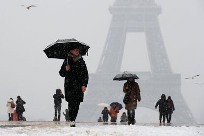 Un grupo de turistas utiliza paraguas para protegerse de la nieve en la explanada de Trocadero de París.