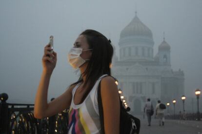 Un mujer toma una fotografía con su teléfono móvil en un Moscú cubierto por el humo.