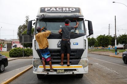 Migrantes venezolanos limpian parabrisas de autos en las calles de Lima (Perú), en marzo de 2020.