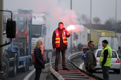 Un hombre sujeta una bengala durante una protesta de camioneros en la A84 cerca de la ciudad francesa de Caen.