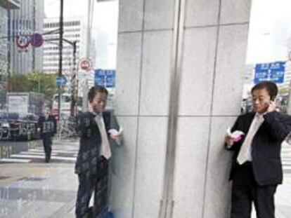 Un hombre de negocios delante de un tablero electrónico que muestra precios de las acciones del Nikkei