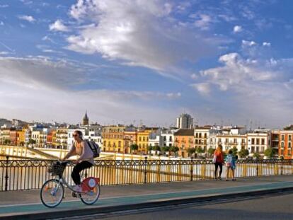 Una joven cruza el puente de Isabel II en una de las bicicletas del servicio p&uacute;blico. 