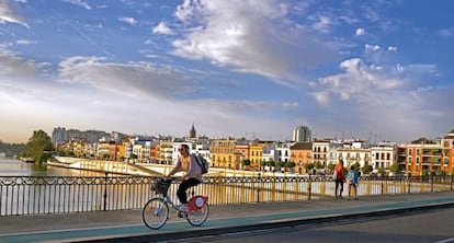 Una joven cruza el puente de Isabel II en una de las bicicletas del servicio p&uacute;blico. 