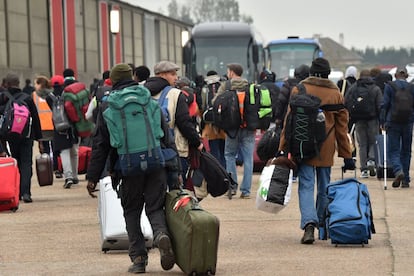 Migrantes llevan sus pertenencias hacia abutobuses para abandonar el campamento de Calais (Francia).