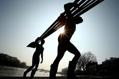 Dos miembros del equipo de remo masculino de Cambridge sacan su embarcación del río Támesis después de un entrenamiento previo a la competición BNY Mellon Boat Race que se celebra en Londres.