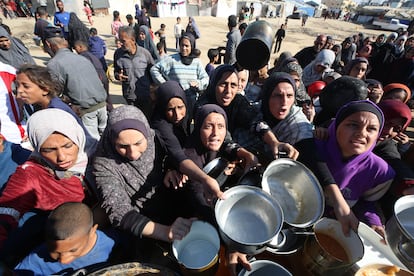 Mujeres palestinas intentan conseguir comida distribuida por una ONG en Deir Al Balah, en Gaza, este lunes.