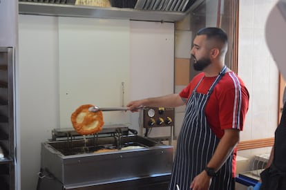 Un cocinero extrae de la freidora la masa del lángos ya frita lista para disponer encima los ingredientes. 