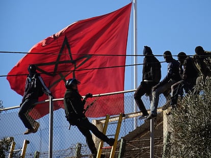 Un agente de la Guardia Civil intenta convencer a un grupo de subsaharianos que baje de la valla tras intentar entrar en Melilla en 2014.