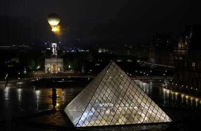 A balloon carrying the Olympic flame flies over Paris above the Louvre.