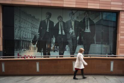 Una mujer cruza frente a una gigantesca fotografía de Los Beatles en Liverpool