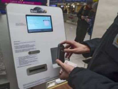 Una persona se identifica con su móvil en un cajero automático que dispensa bitcoines, en una tienda de discos. EFE/Archivo