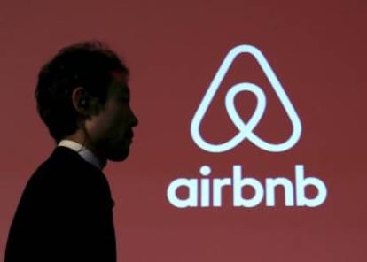 Un hombre pasa delante del logo de Airbnb en una conferencia en Tokio.  