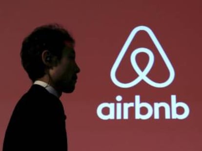 Un hombre pasa delante del logo de Airbnb en una conferencia en Tokio.  