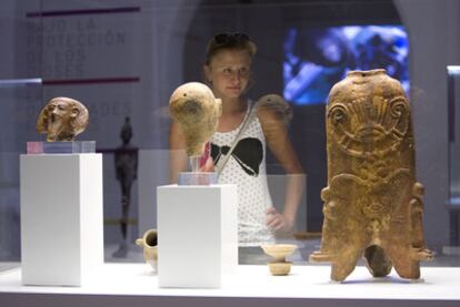 Una joven observa varias piezas incluidas en la exposición <i>Cádiz y Huelva, puertos fenicios del Atlántico</i>.