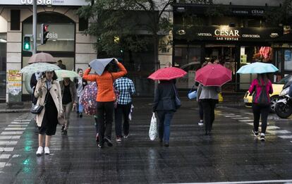 Varias personas se protegen de la lluvia en Madrid donde las precipitaciones han llegado a ser "puntualmente fuertes", el 17 de octubre de 2017.