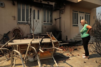 Una mujer observa los daños en su vivienda provocados por el incendio forestan en Dionysos, este lunes.