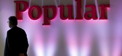 Un hombre frente a un logo de Banco Popular.