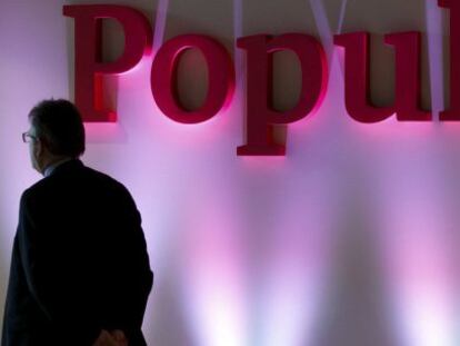 Un hombre frente a un logo de Banco Popular. 