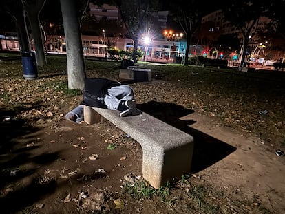 Un migrante se protege con una bolsa de basura mientras duerme, en un parque de Palma.