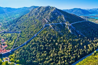 Construidas en el siglo XIV para proteger la producción de las salinas de Ston, puerto de la costa sur de Croacia ubicado en el istmo que une la península de Pelješac con el continente (a unos 60 kilómetros al norte de Dubrovnik), los 5,5 kilómetros de recorrido de esta muralla –una de las más largas de Europa– se pueden recorrer caminando gracias a su buen estado de conservación. Los muros trepan vertiginosamente (en dos secciones a diferente altura) por la empinada colina que custodia la espalda de Ston (a la izquierda, en la imagen), y tras llanear la ladera, descienden abruptamente después hasta conectar con la vecina localidad de Mali Ston, al otro lado del cerro. Más información: <a href="https://croatia.hr/es-ES" target="_blank">croatia.hr</a>