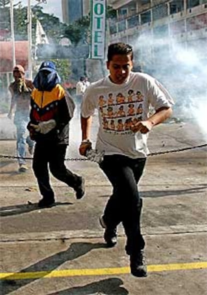 Opositores de Hugo Chávez huyen de los gases lacrimógenos de la policía durante los disturbios de ayer en Caracas.