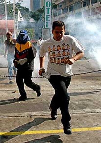 Opositores de Hugo Chávez huyen de los gases lacrimógenos de la policía durante los disturbios de ayer en Caracas.