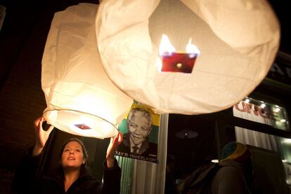 Uma mulher acende uma lâmpada de papel no exterior do restaurante Madiba, chamado assim em honra ao ex-presidente sul-africano Nelson Mandela, no bairro do Brooklyn, Nova York, 5 dezembro de 2013.