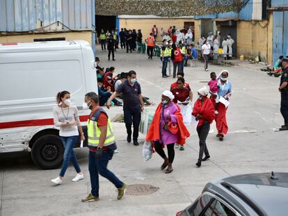 Profesionales sanitarios atienden a varias personas en la nave de primera acogida del polígono del Tarajal (Ceuta).