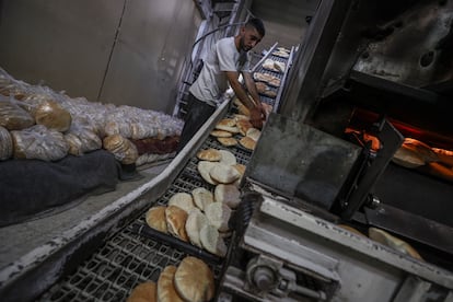 El pan recién horneado avanza por una cinta transportadora en una panadería del Programa Mundial de Alimentos (PMA) tras el ingreso de una cantidad limitada de harina a la Franja, este jueves.