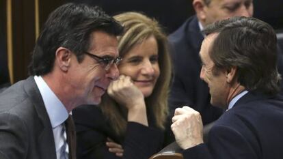 La ministra de Empleo, Fátima Báñez, escucha la conversación entre el responsable de Industria, José Manuel Soria, y el portavoz del PP, Rafael Hernando.