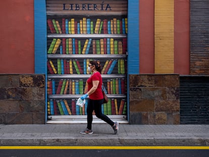 Una mujer pasa por delante de una librería cerrada en Sevilla, en el día internacional del libro.