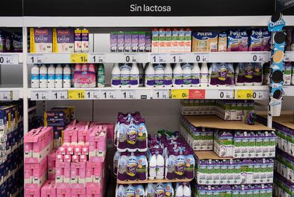 Un estante de un supermercado con botellas de distintas marcas de leche.