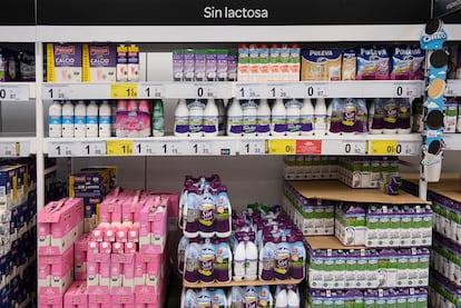 Un estante de un supermercado con botellas de distintas marcas de leche.