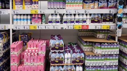 Un estante de un supermercado con botellas de distintas marcas de leche.