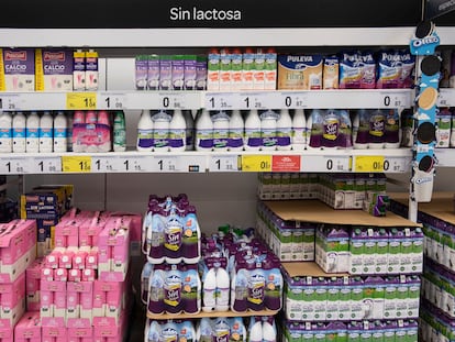 Un estante de un supermercado con botellas de distintas marcas de leche.