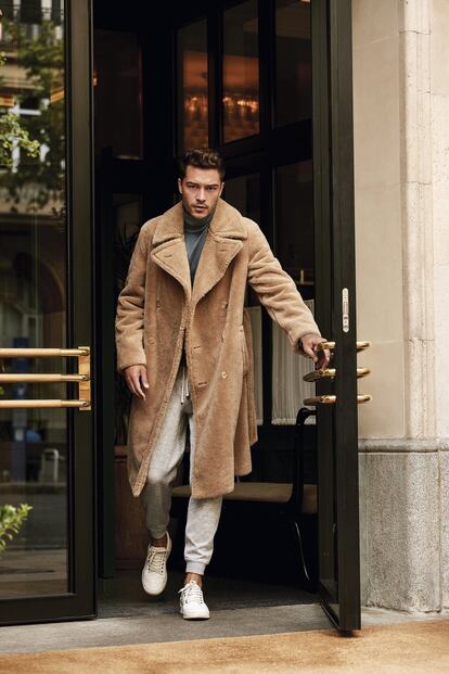 Abrigo beis de pelo de Ralph Lauren Purple Label, pantalón de chándal de Brunello Cucinelli, jersey azul de Hermès y deportivas blancas de Louis Vuitton.