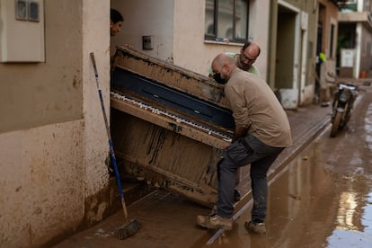 En la imagen, Lupe Murcia y Miguel Ramírez retiran de su casa con la ayuda de otra persona un piano inutilizado por el agua el pasado 5 de noviembre. El piano, que ahora lo utilizaba su hija, lo compró ella cuando era una estudiante.