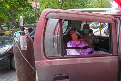 Una mujer respira con la ayuda de una bombona de oxígeno en el interior de un vehículo en Ghaziabad (India). El país ha notificado este jueves nuevas cifras máximas de casos y muertos por coronavirus, rozando los 380.000 pacientes y los 3.700 decesos, en una jornada en la que el país asiático ha superado además el umbral de los 18 millones de contagios desde el inicio de la pandemia.