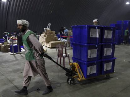 Trabajadores afganos llevan urnas hacia camiones para que sean distribuidas, este lunes en Kabul.