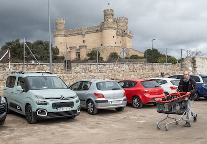 Un hombre con el carro de la compra en el párking público de Manzanares el Real, junto al Castillo de los Mendoza.