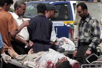 Varias personas junto a los cuerpos de dos civiles asesinados ayer en Bagdad.