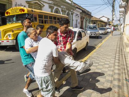 Varios hijos de Antonio ayudan a una persona con deficiencia motriz a cruzar una calle de Granada.