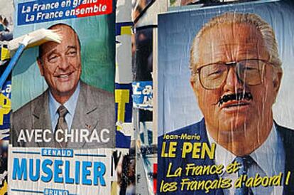 Un voluntario de Chirac coloca un cartel del líder republicano junto a otro de Le Pen con un bigote pintarrajeado.