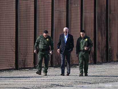 Joe Biden camina escoltado por dos agentes de la Patrulla Fronteriza junto al muro con México.