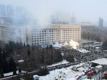 Columnas de humo se elevan ante un grupo de manifestantes junto al Ayuntamiento de Almaty (Kazajistán).