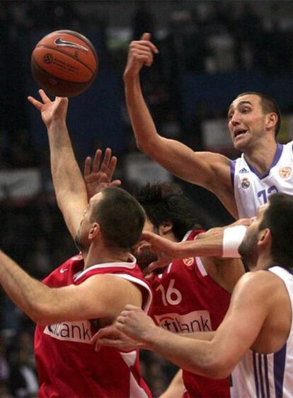 Los jugadores del Olympiakos Georgios Printezis y Nikola Vujcic pelean por el control del balón con los jugadores del Real Madrid Felipe Reyes y Tomas Van Den Spiegel.