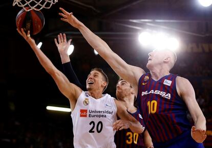 El escolta estadounidense del Real Madrid, Jaycee Carroll, entra a canasta ante los jugadores del Barcelona Lassa, Victor Claver y el letón Roland Smits.