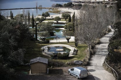 La zona de piscinas y playa artificial con las obras del hotel paralizadas a la derecha y el pantano de Valdeca?as al fondo.